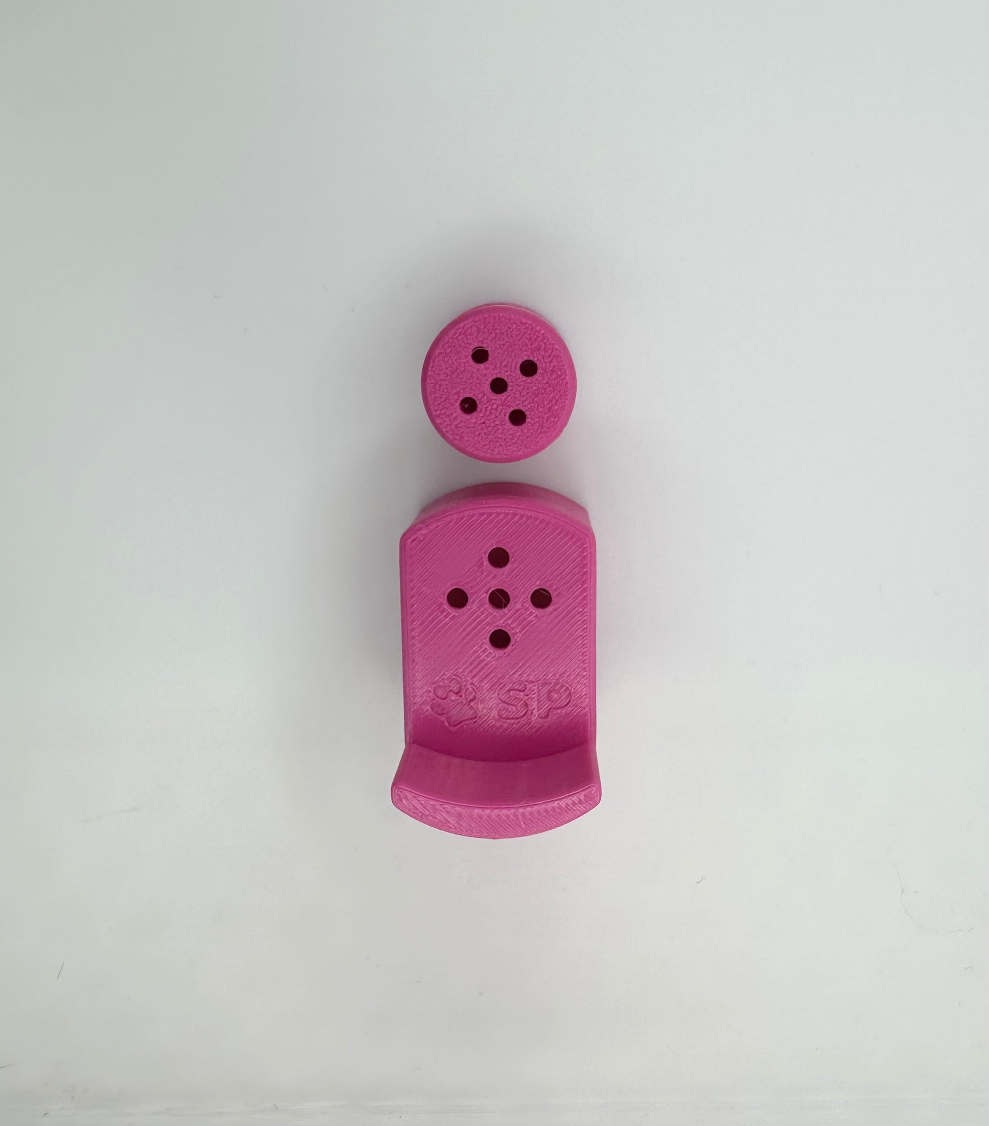 A single set of a 3D-printed Sniffy Prints pairing extension and Tiny Hide for K9 nosework in Pink. The extension in the image is magnetic and designed to go over Sniffy Prints Tiny Hide. The extension features a curved base to hold a treat, multiple small holes for odor to pass through, and an embossed 'SP' logo with a paw print.