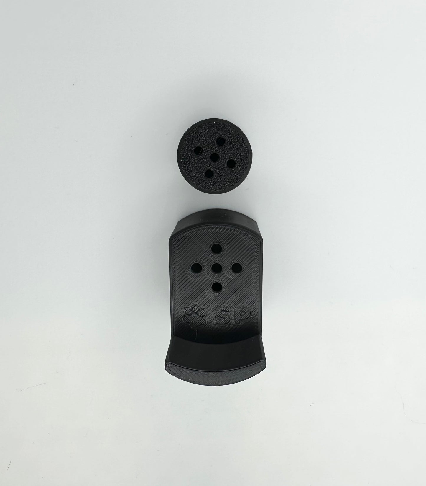 A single set of a 3D-printed Sniffy Prints pairing extension and Tiny Hide for K9 nosework in Black. The extension in the image is magnetic and designed to go over Sniffy Prints Tiny Hide. The extension features a curved base to hold a treat, multiple small holes for odor to pass through, and an embossed 'SP' logo with a paw print.