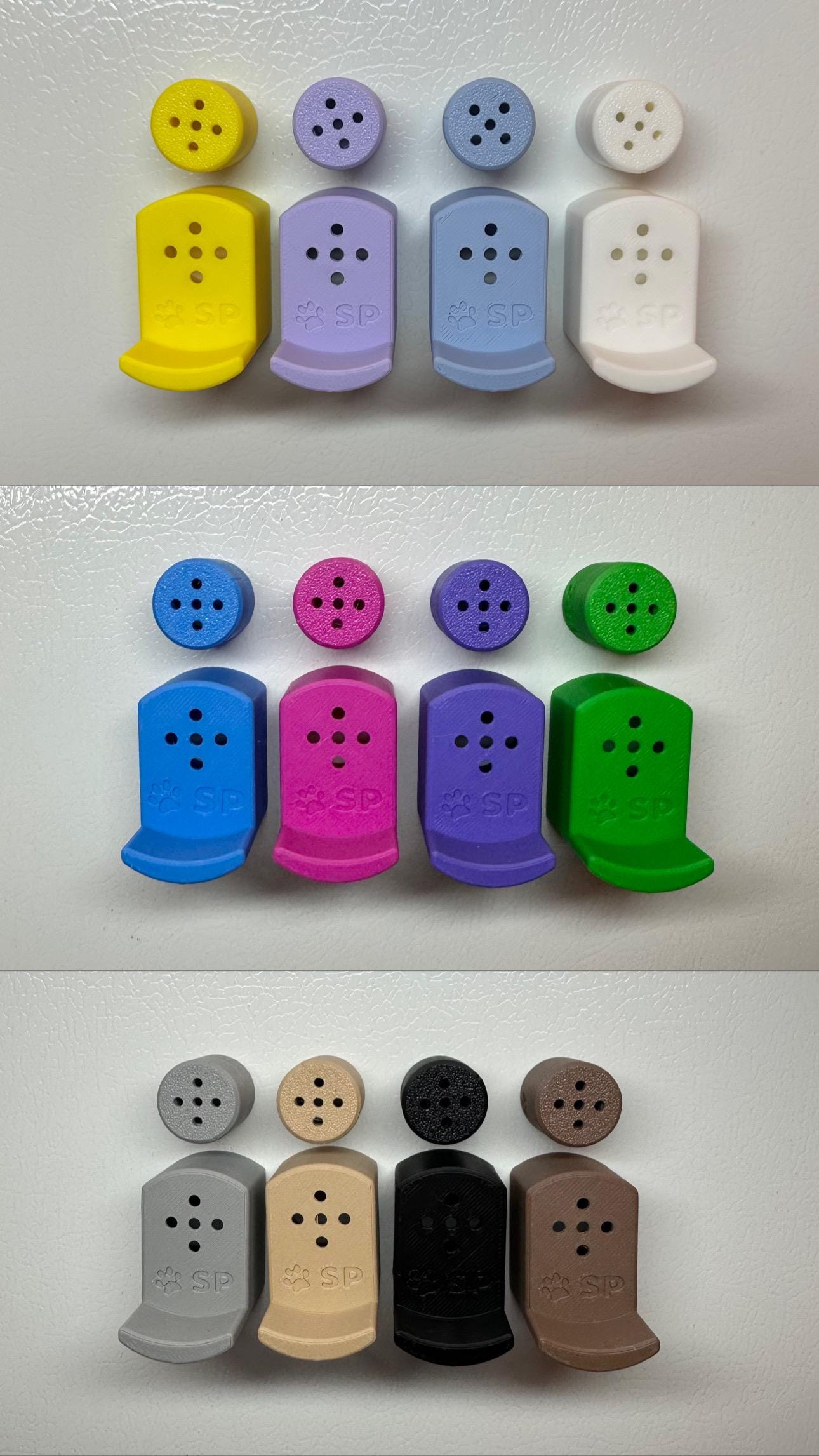 Twelve 3D-printed Sniffy Prints pairing extensions + Tiny Hides for K9 nosework. The extensions and in the image are magnetic and designed to go over Sniffy Prints Tiny Hides which are displayed above each extension. TEach piece features a curved base to hold a treat, multiple small holes for odor to pass through, and an embossed 'SP' logo with a paw print.