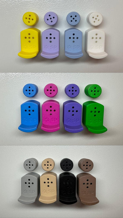 Twelve 3D-printed Sniffy Prints pairing extensions + Tiny Hides for K9 nosework. The extensions and in the image are magnetic and designed to go over Sniffy Prints Tiny Hides which are displayed above each extension. TEach piece features a curved base to hold a treat, multiple small holes for odor to pass through, and an embossed 'SP' logo with a paw print.