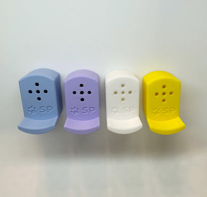 A set of four 3D-printed Sniffy Prints pairing extensions for K9 nosework. The extensions in the image are magnetic and designed to go over Sniffy Prints Tiny Hides. They are ice blue, perwinkle, white and yellow. Each piece features a curved base to hold a treat, multiple small holes for odor to pass through, and an embossed 'SP' logo with a paw print.