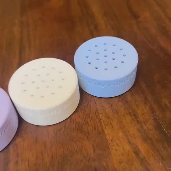 A video showing multiple Sniffy Prints odor pods for nosework arranged in a row, highlighting their design and colors